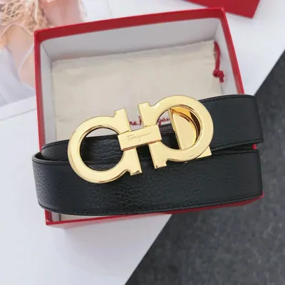 A black leather belt with a large gold buckle, coiled inside an open red presentation box