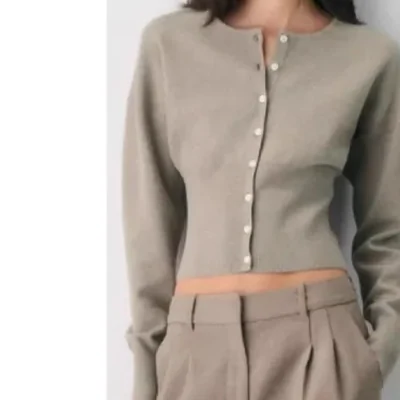 A cropped button front knit cardigan worn with wide trousers, shown on a model from the neck down