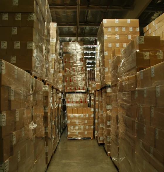 Aisle of a Chinese warehouse with shrink wrapped pallets stacked to the ceiling on both sides